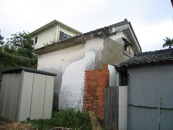 外壁が白漆喰塗りされ、一部に煉瓦が貼られている土蔵のような建物が立っている様子の写真