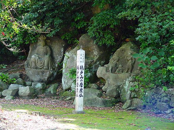 杭の後ろの古い岩に閻魔大王像と四天像が彫られている写真