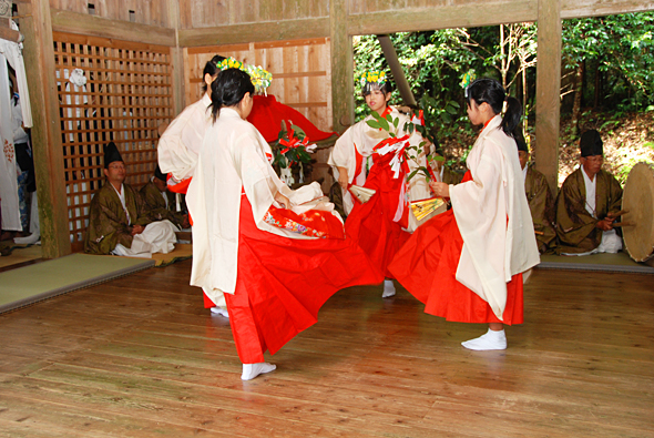 神社の板の間で踊る四人の巫女の写真