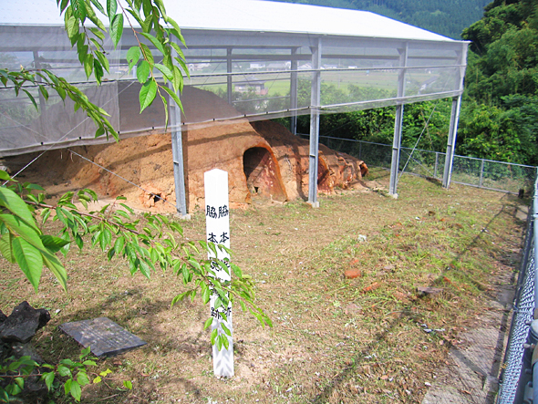 脇本焼窯跡と書かれた白い杭の奥にある白い屋根に覆われた焼窯の写真