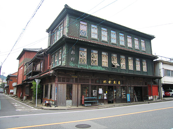 角地にある緑色の壁の三階建ての建物の写真