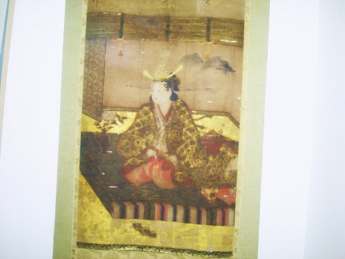 冠をつけた女性が畳の上に座っている様子が描かれた掛け軸の写真