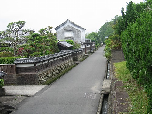 石垣が並んだ道路と石垣の屋敷内から庭木が見え、城下町を偲ぶような町並みの写真