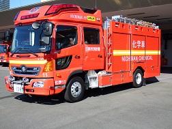 後部に大文字で「化学車」と書かれた赤色のボディの化学車を右斜め前から撮影した写真