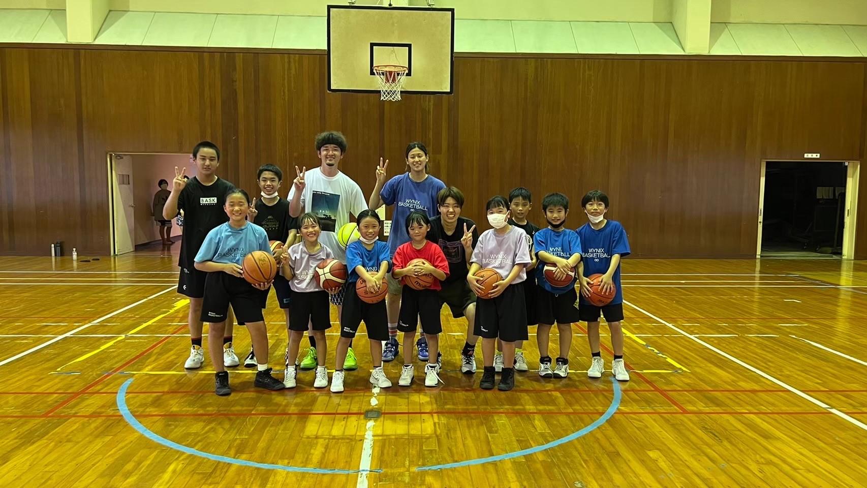 体育館のバスケットゴール前で、井上選手らとバスケットボールを持った子供たちが一緒に並んだ集合写真