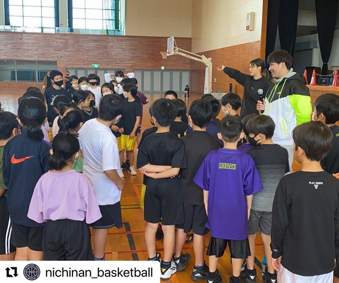 体育館で周りに集まった参加者の子どもたちの前に立ち、マイクを持っているゲストの清水氏と、隣で右手を右上に向けて伸ばしている女性の写真