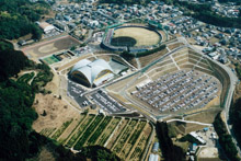 円形の野球スタジアムとシルバーの屋根がついた南郷くろしおドームが隣接している様子を上空から撮影した中央公園の写真