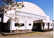 白い半円形の建物の榎原地区体育館の外観写真