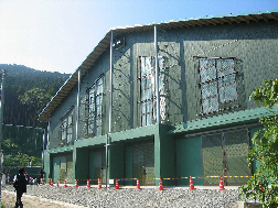 緑色の外壁で三角屋根の建物の雨天練習場の外観写真