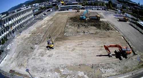 3台のショベルカーとダンプカー1台が新庁舎建設予定地で工事を行っている写真
