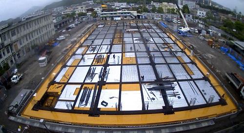 奥行きのある長方形をした新庁舎建設部分の1階床が沢山の長方形に区切られ配筋が施されている様子を写した写真