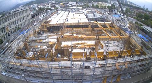 新庁舎の周りに足場が組まれ、手前側が黄色の板のようなもので仕切られ、奥側は天井が出来ている1階型枠工事の様子を写した写真