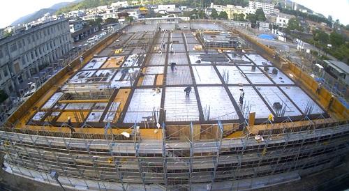 新庁舎の周りに足場が組まれ、2階床部分が沢山の長方形に区切られ配筋工事が施されている様子の写真