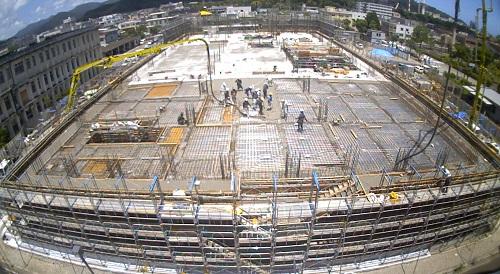 新庁舎の周りに足場が組まれ、コンクリートポンプ車から2階床部分にコンクリートを流し込んでいる作業の様子を写した写真