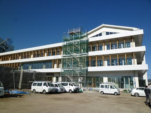 白を基調とした外壁で3階建ての新庁舎正面の一部に足場が組まれている写真