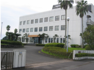 3階建てで白い壁の日南下水終末処理場の建物外観を道路入口付近から撮影した写真