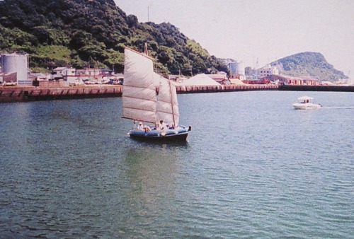 港湾内に浮かぶ小さく簡易な帆船の写真