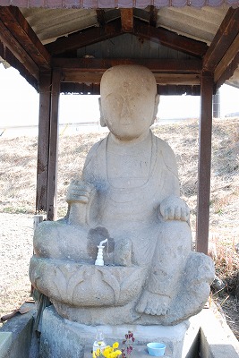社の中で片膝を立てて座った地蔵菩薩像の写真