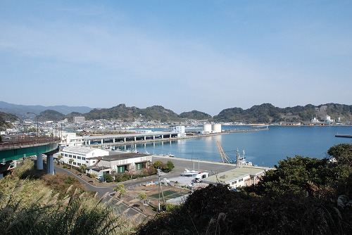 でこぼこした山に囲まれた目井津港の写真