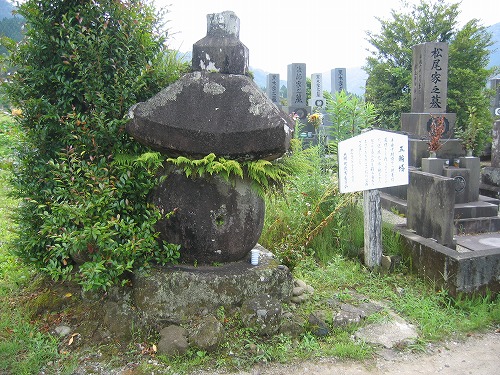 墓石が並ぶ墓地の一角にある、看板とともに設置されている五輪塔の写真