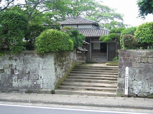 道路沿いに石垣が並んでおり、奥に建っている旧伊東伝左衛門家の武家屋敷入口に繋がるように石畳の階段が設置されている写真