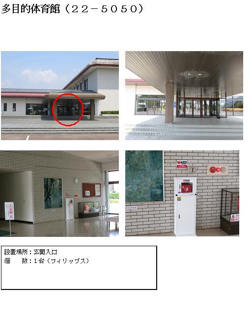 多目的体育館（22-5050） 上段左：日南市総合運動公園多目的体育館横にある横長の建物の入り口部分に赤丸がされている写真。上段右：左側に1本の柱が立っている奥にガラスドアの玄関入口が写っている写真。中段左：タイル張りの壁に掲示板や絵画が飾られている間に白いAED収納ケーススタンドが設置されている写真。中段右：白いAED収納ケーススタンドの中に収納されている赤いAEDを正面から写した写真。下段：「設置場所：玄関入口 個数：1台（フィリップス）」と書かれた案内文