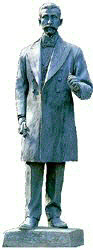 蝶ネクタイとフロックコートを着用して立っている小村寿太郎像の写真