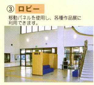 3ロビー「移動パネルを使用し、各種作品展に利用できます。」階段や青色のソファが向かい合わせに設置されている広いロビーの写真
