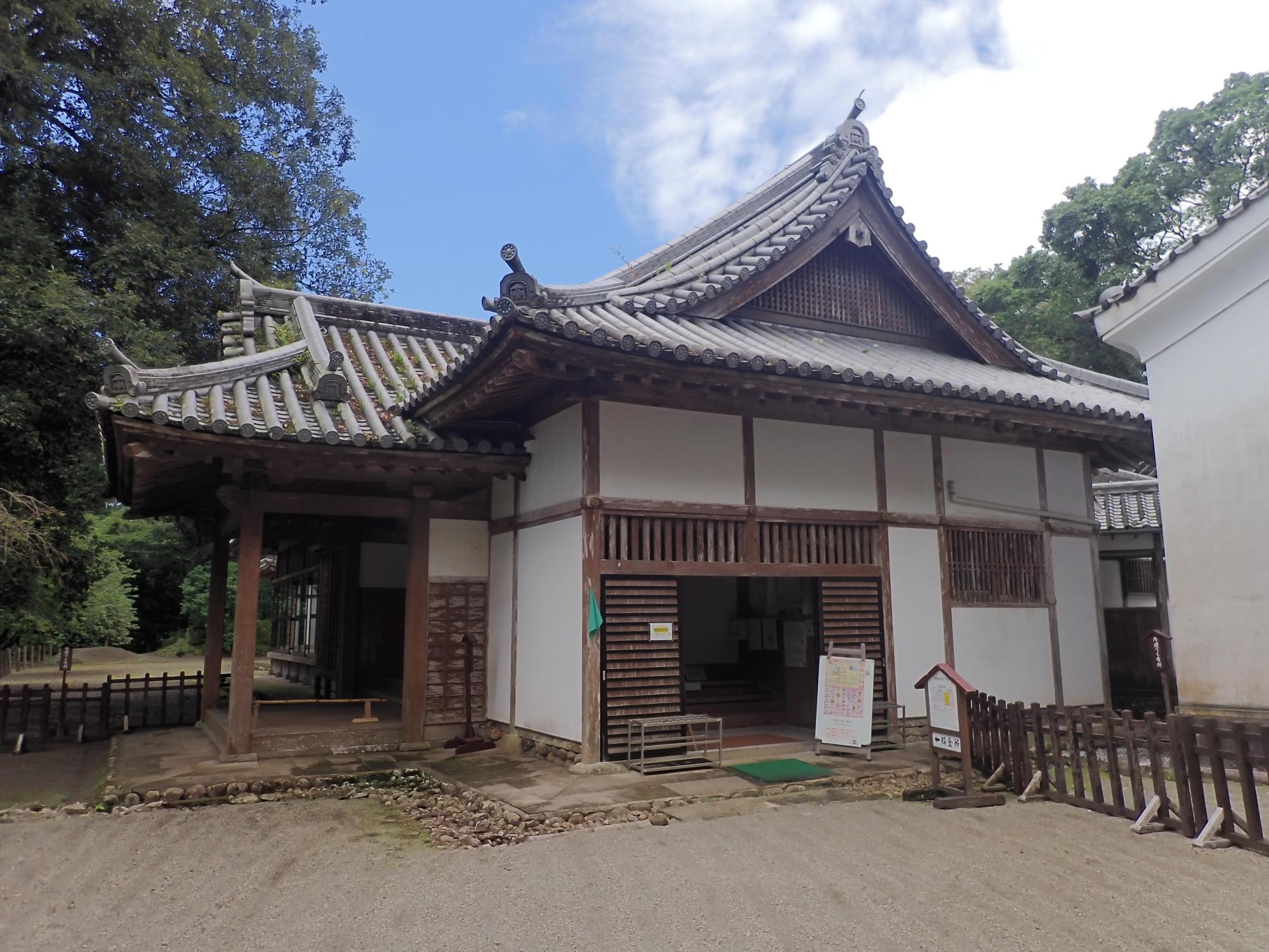 木々に囲まれた白壁で入母屋造り、瓦葺屋根の松尾の丸外観写真