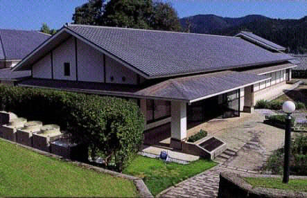 きれいに整備された庭の奥に瓦屋根の大きな建物が建っている写真