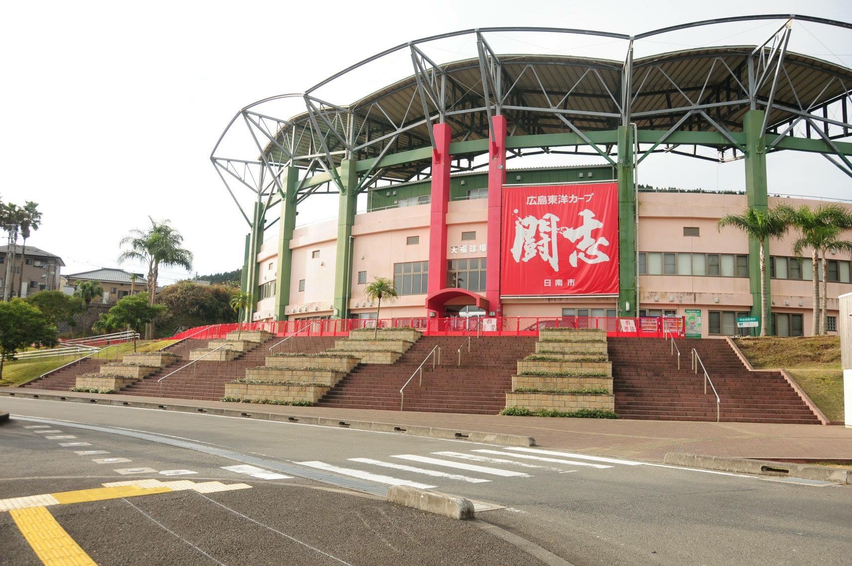 広島東洋カープ 闘志 日南市 と書かれた大きな赤い横断幕が飾られた野球場入口外観の写真
