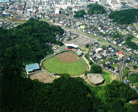 森林と住宅街の中間に位置し、扇型の球場がある天福公園を上空から撮影した写真