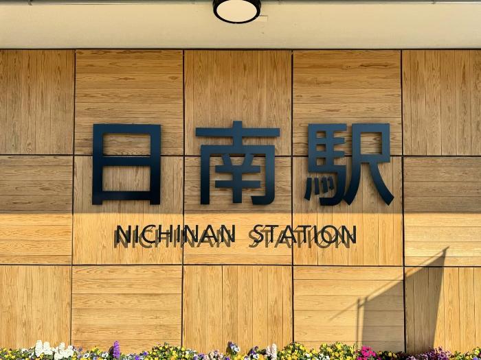 日南駅の飫肥杉製の壁に黒文字で日南駅名表示（写真）